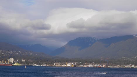 a view of the mountains near vancouver downtown with a boat speeding through the water