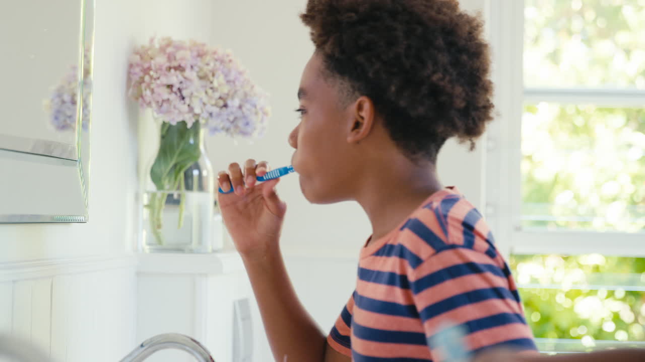 Brother And Sister Sitting In Bathroom At Home Brushing Teeth Together