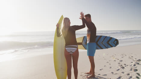 pareja caucásica con tablas de surf en la playa