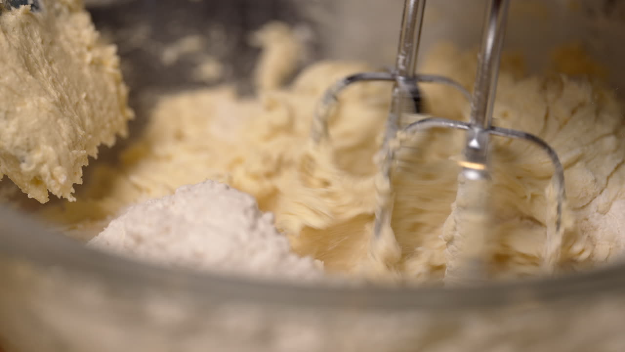 Creamy delicious batter with butter and eggs being mixed in a bowl - isolated close up in slow motion