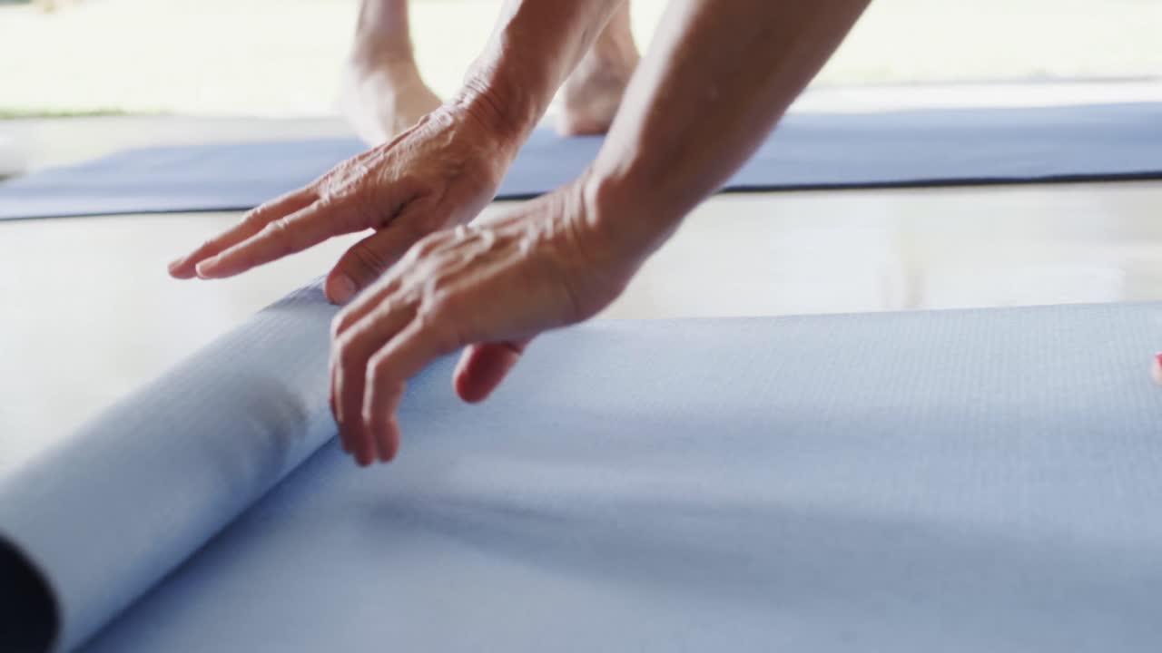 un primer plano de varios ancianos preparando esteras de ejercicio para la clase de pilates, sin alteraciones, en cámara lenta.