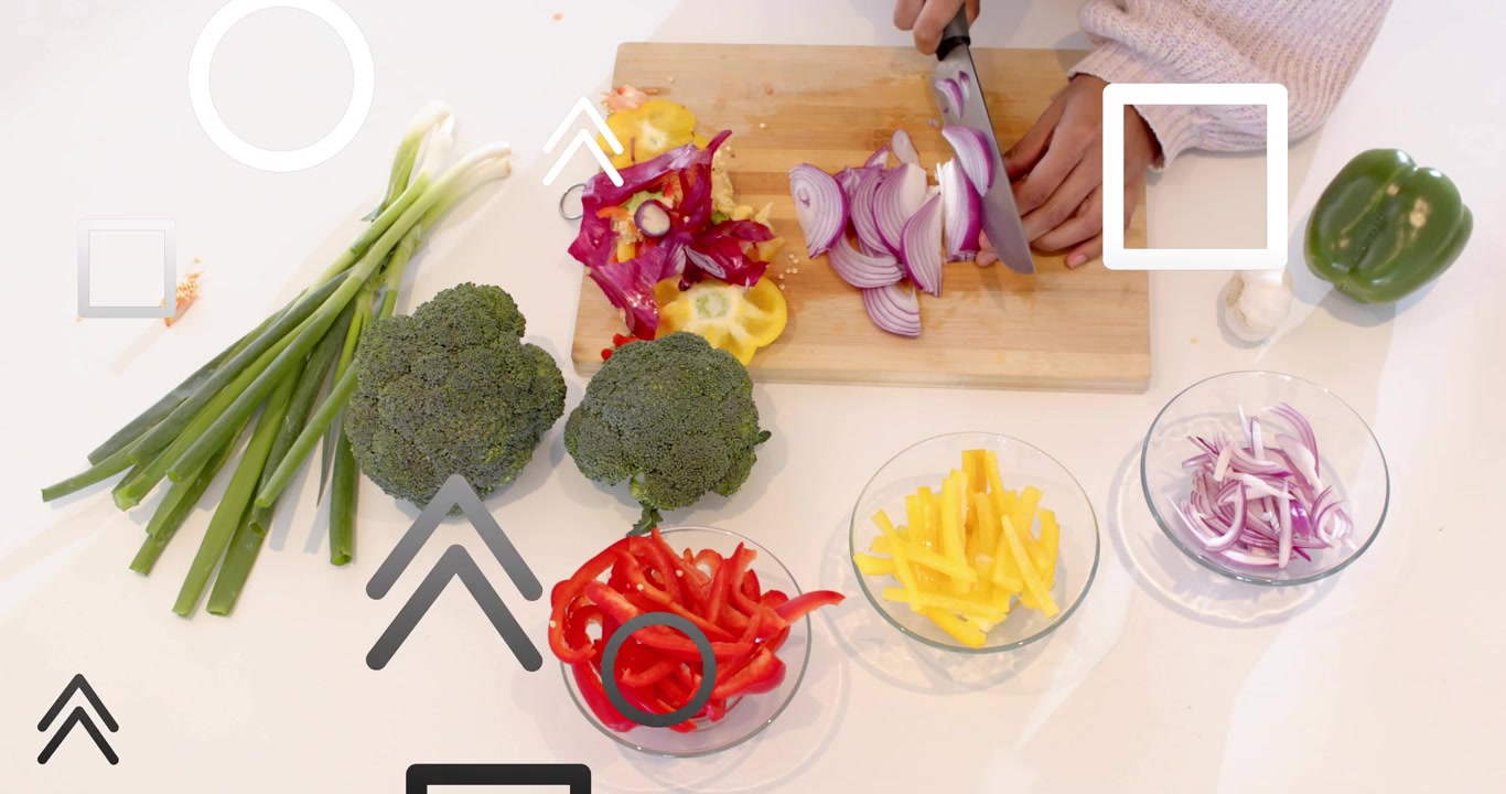 Woman's hands lifting red onion on cutting board, slicing strips into glass bowl for cooking