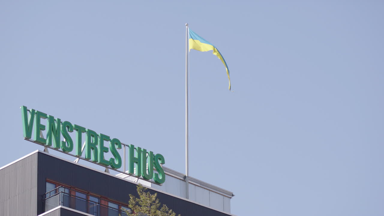Venstres Hus AS sign atop building with waving flag on Youngstorget, Oslo