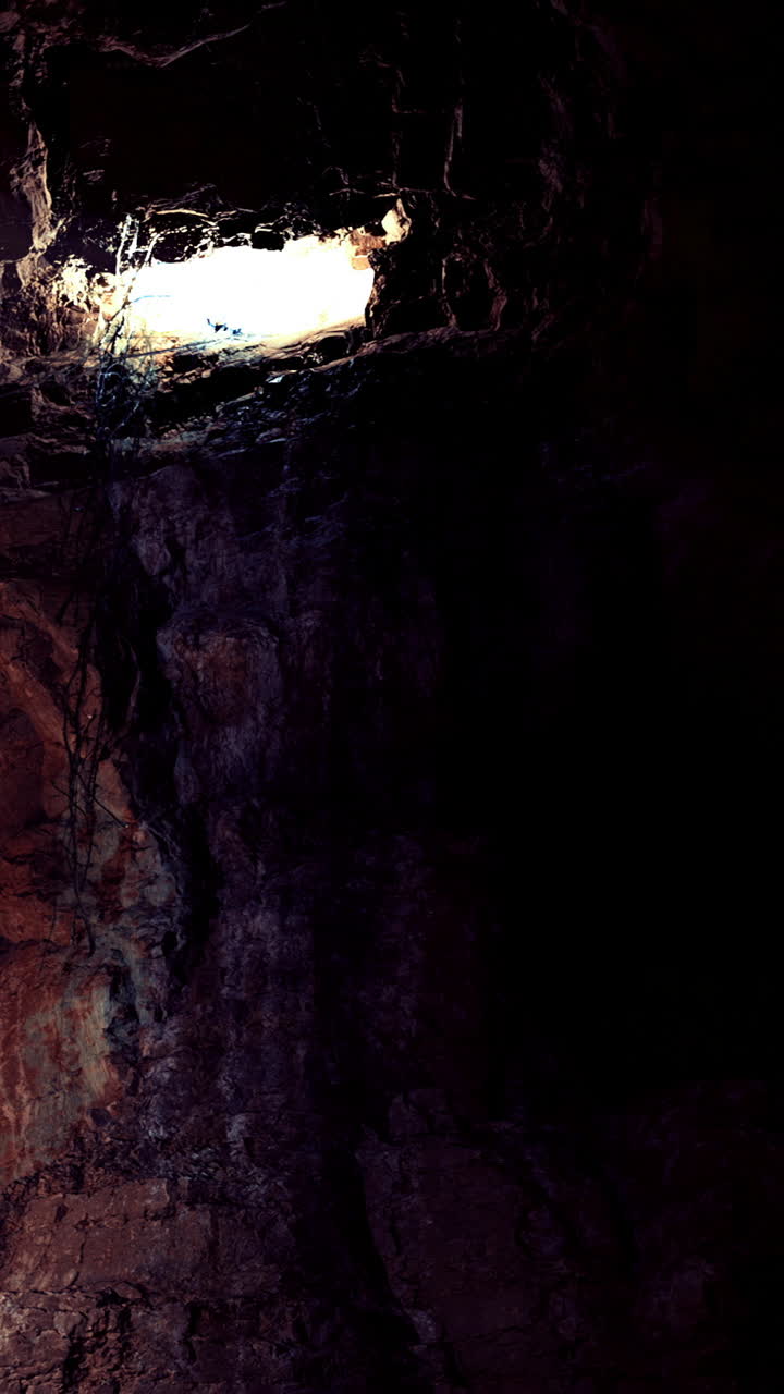 Luce drammatica filtra attraverso formazioni rocciose in una profonda grotta