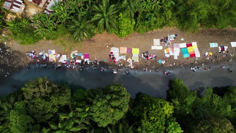 birds eye drone shot of women washing clothes in a river, in sunny africa