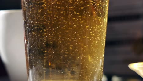 super slow motion shot of bubbling beer in glass with foam