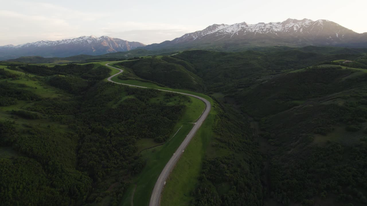 camino sinuoso, picos de montañas cubiertos de nieve al atardecer, vista panorámica aérea
