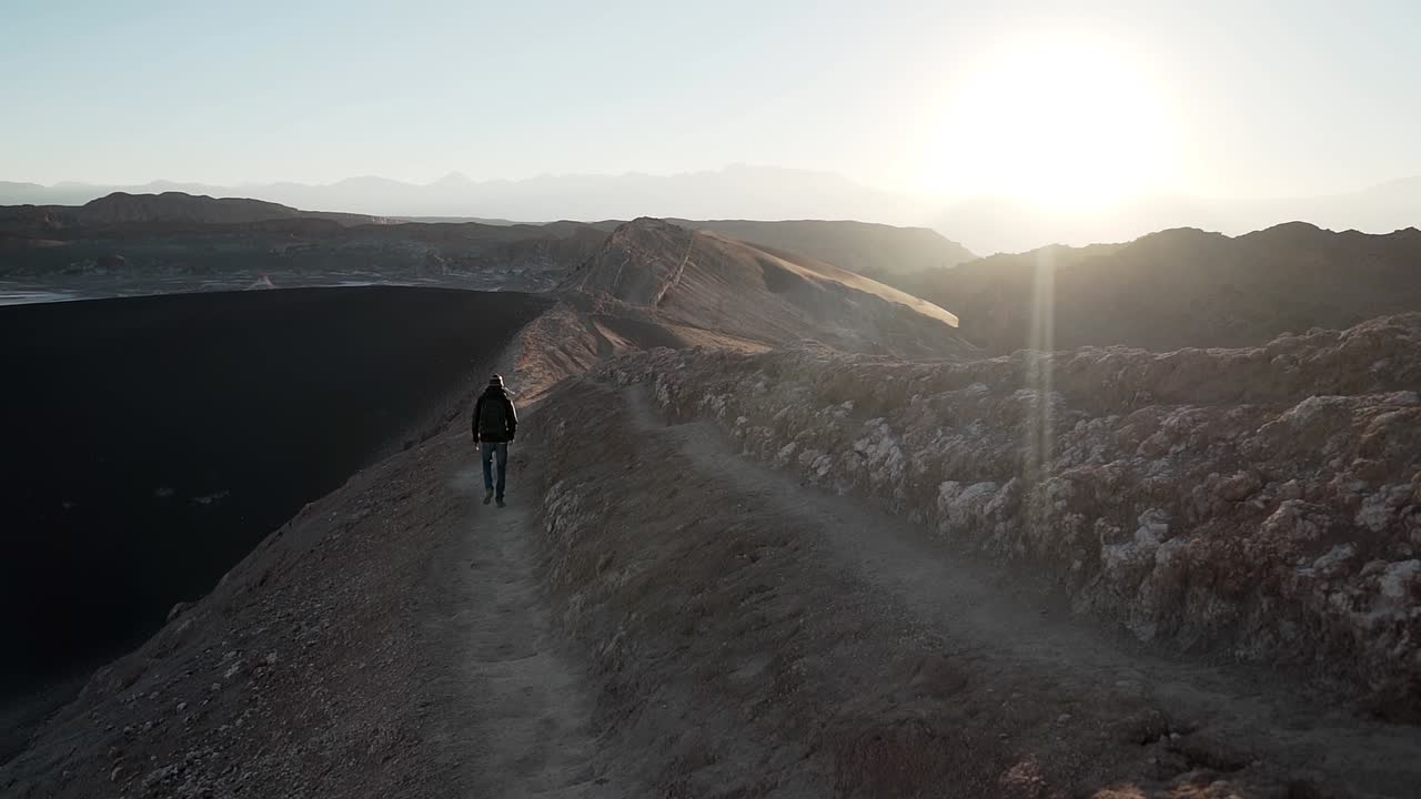 hombre caminando en una montaña de trekking al amanecer en el desierto