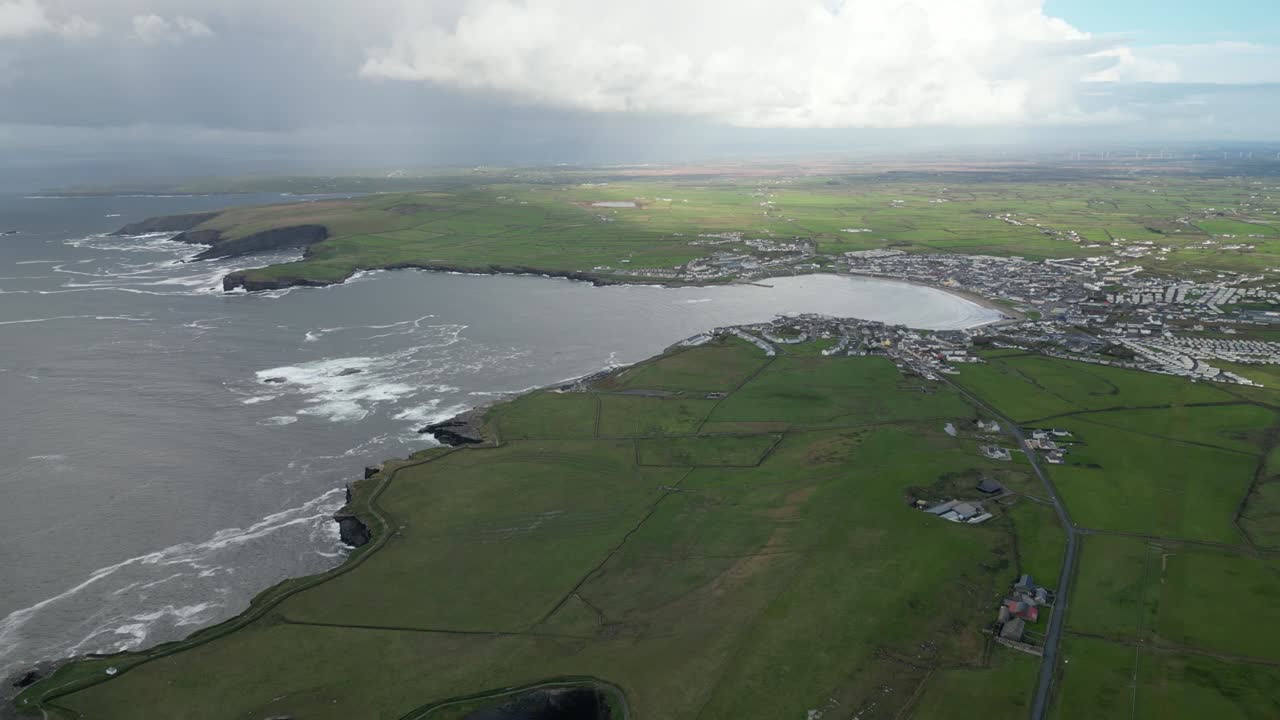 어두워지면 구름이 가득한 하늘 아래 격렬한 바다와 초록색 이 있는 해안 도시