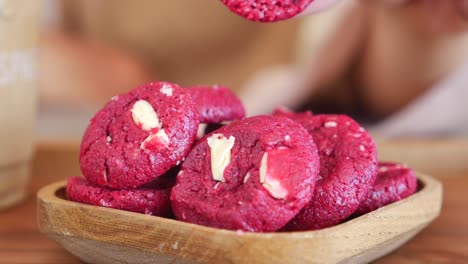 close up of a hand reaching for a red velvet cookie