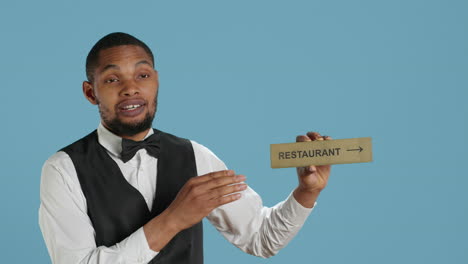 Doorman-bellhop-showing-the-restaurant-direction-with-a-hotel-sign