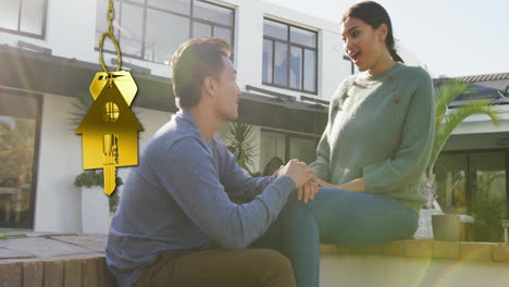 animation of gold house key and key fob over happy diverse couple in garden at home