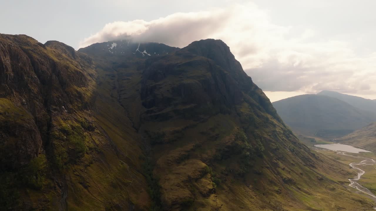 Aerial drone footage of Bidean Nam Bian, the highest mountain in Glencoe, Scotland, covered in snow. Sweeping views of snowy peaks, deep valleys, and dramatic Highland scenery