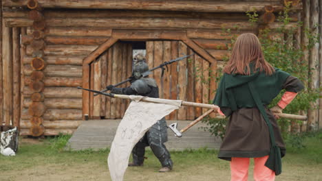 duel between dark knight and young female near log building