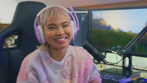 portrait of woman gaming at home sitting at desk wearing headphones for live stream