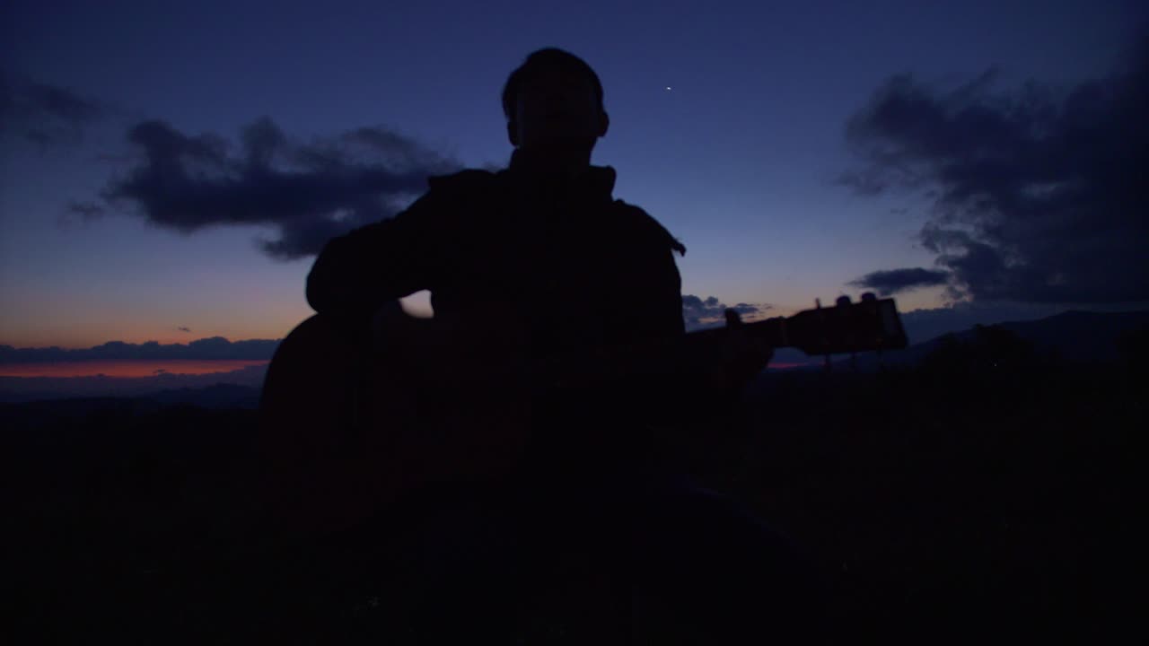 베트남 하늘에서 극적인 색상으로 황혼에 기타를 연주하는 남자의 실루엣