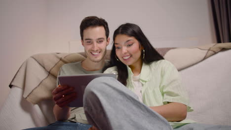 bottom view of couple watching comic movie on tablet while sitting on the floor at home