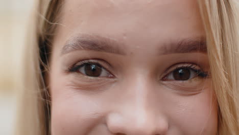 extreme closeup macro portrait of young face blonde womans eyes looking at camera smiling