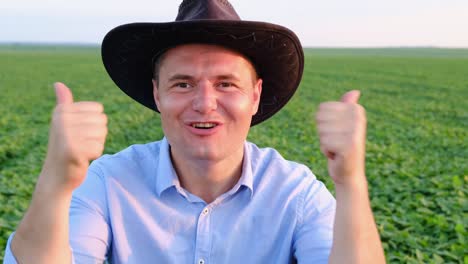 portrait of a young farmer in a blue shirt and hat and looking at the camera at sunset portrait of a young farmer in a blue shirt and hat and looking at the camera at sunset in the field agricultural land west landscape agriculture