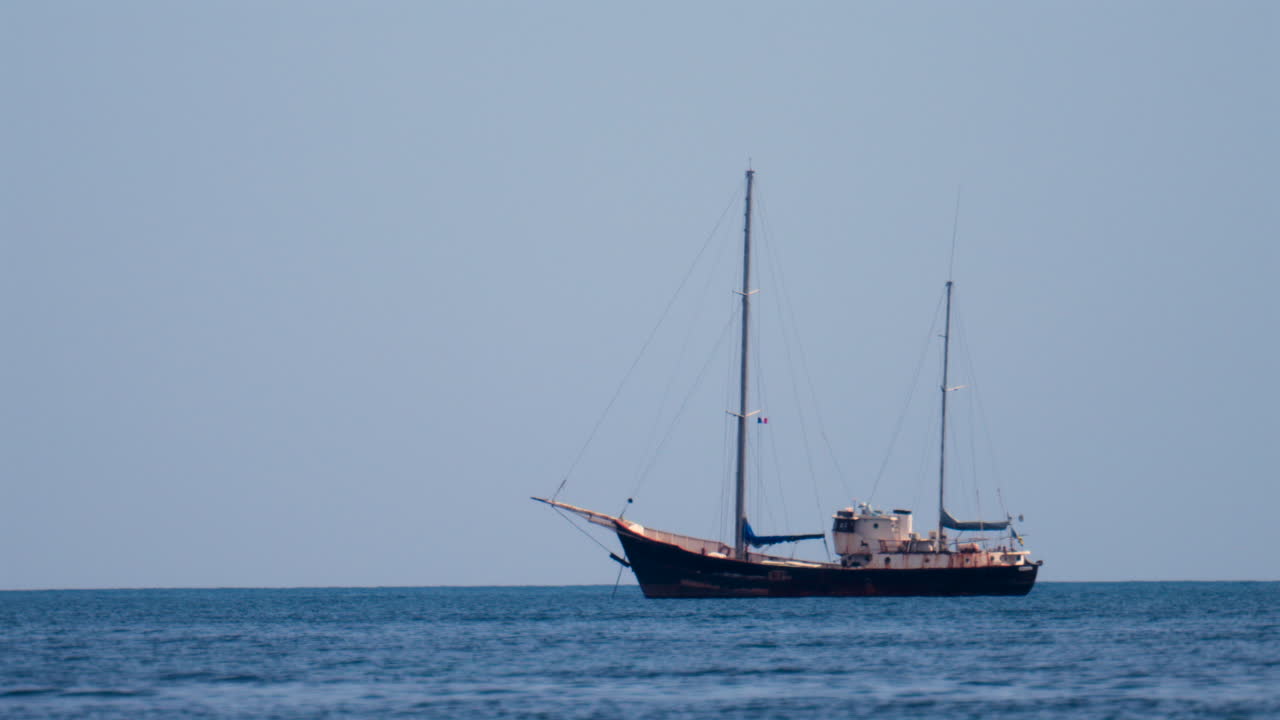Distant view of a rusty boat moving on the sea in the south of France, on a cloudy day