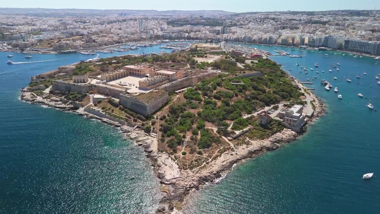 Forte Manoel sull'Isola di Manoel, Malta, con bastioni a forma di stella e mura difensive accanto al porto mediterraneo, circondato da barche e dalla costa urbana in vista aerea