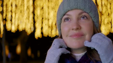 woman with knitted hat in front of christmas lights