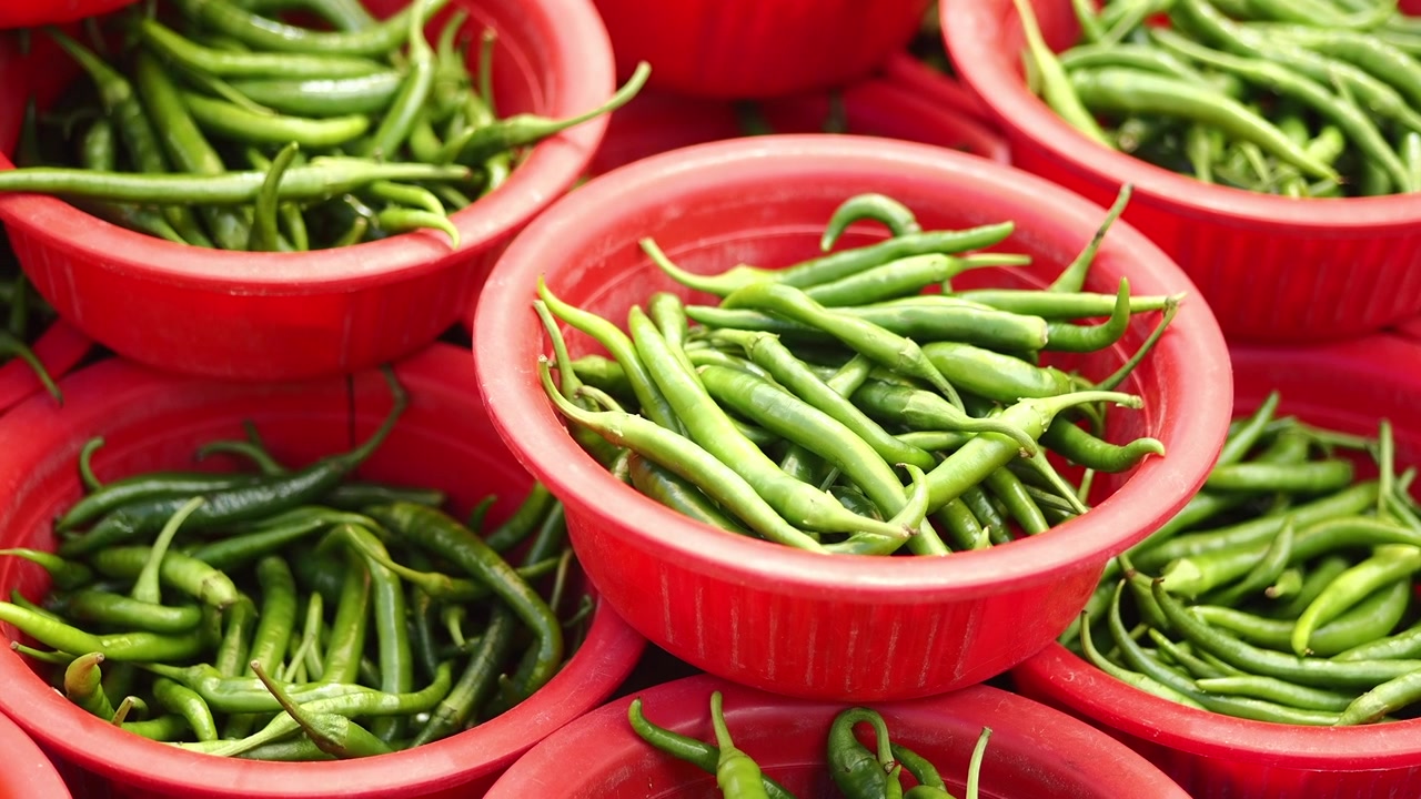 Fresh Green Chili Peppers in Red Plastic Bowls at Market