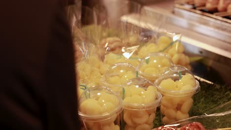 person selects fruit cups at market stall