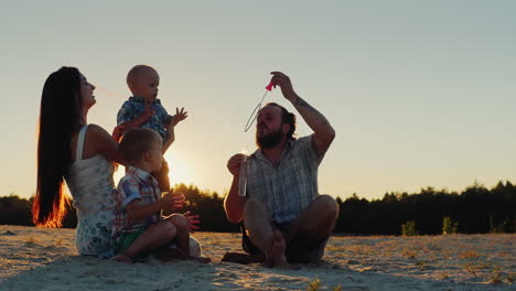 young family having fun with two kids - blow bubbles at sunset