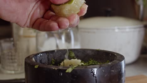 squeezing lemon juice into a black ceramic bowl with herbs and spices