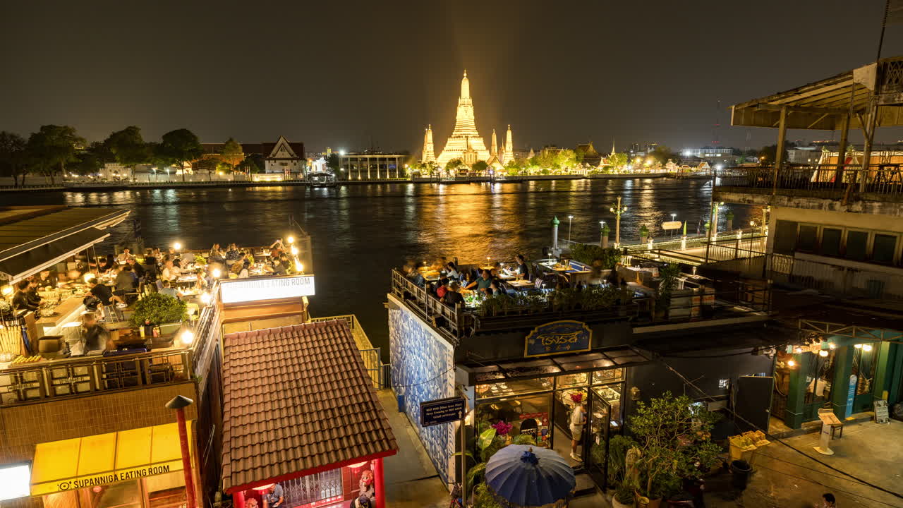Night view of Wat Arun and riverfront restaurants in Bangkok