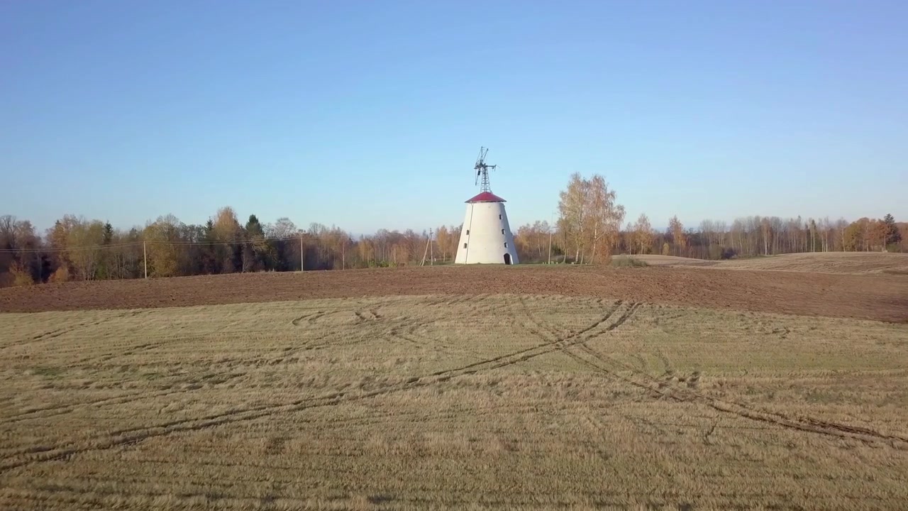 DOLLY ZOOM EFFECT on slow aerial closing in shot of an old abandoned, white stone windmill with the birch trees next to it and freshly cultivated fields all around on sunny Autumn day