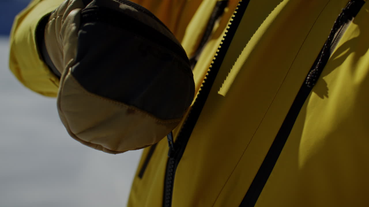 Close up footage of a skier zipping up a ski jacket before skiing at an alpine ski resort in the Verbier region Val de Bagnes Switzerland on a clear bluebird winter day