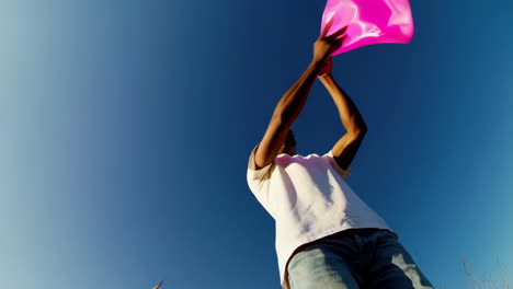 man playing with pink fabric in a sunny field