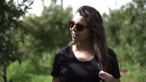 mujer con gafas de sol caminando por una granja de frutas - cámara lenta, primer plano