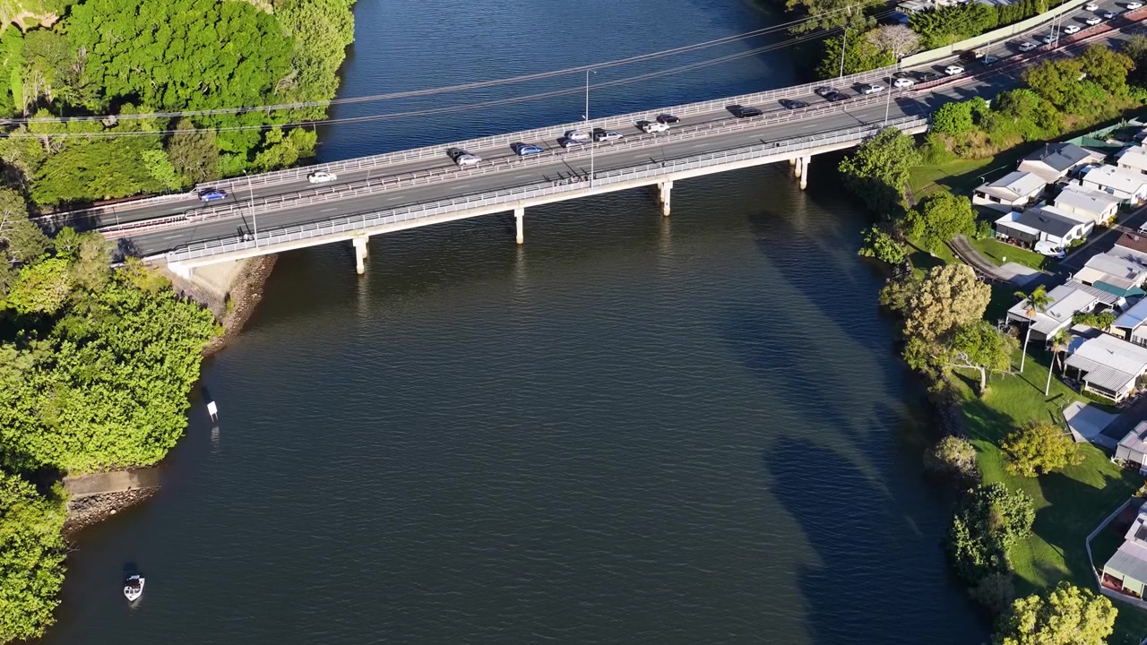 Ripresa aerea con drone mostra auto che attraversano un ponte su un ampio fiume vicino ai sobborghi