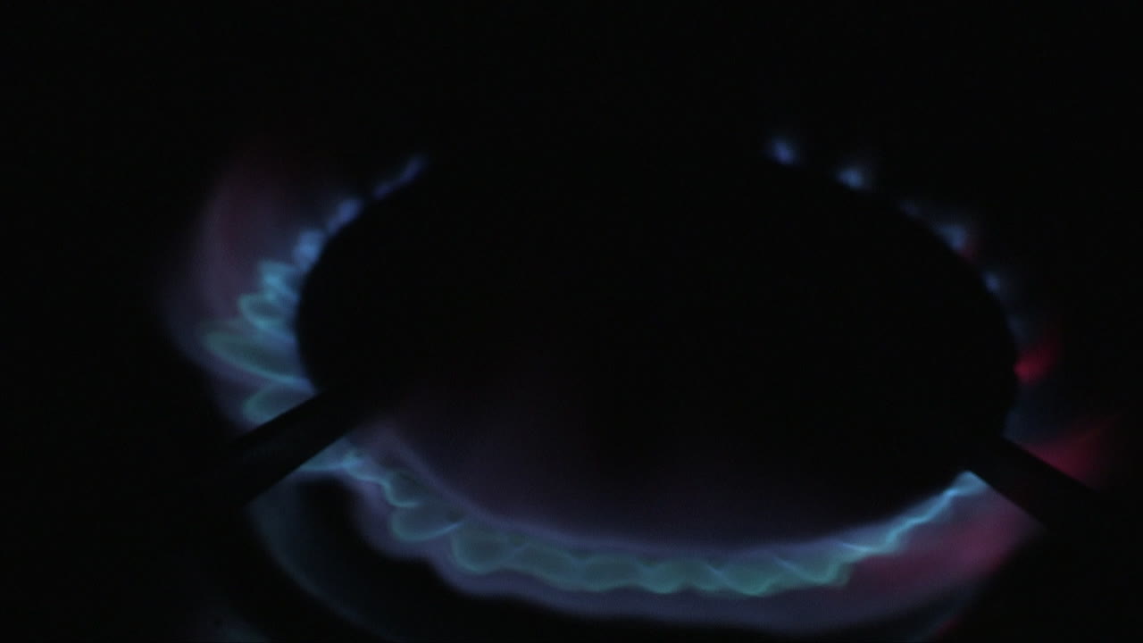 어둠 속에서 불을 밝히고 파란색과 빨간색의 불꽃 원을 형성하는 가스 레인지 버너