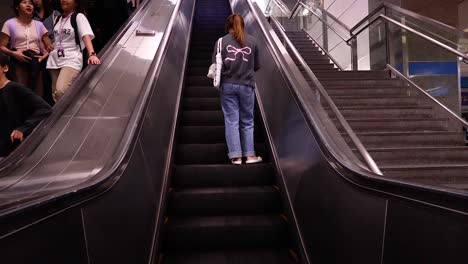 person ascending escalator in subway station