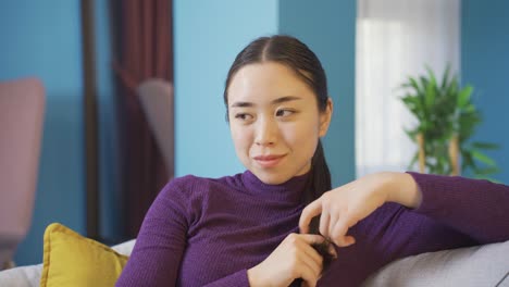 Asiatische-Glückliche-Frau,-Die-Allein-Im-Wohnzimmer-Sitzt.