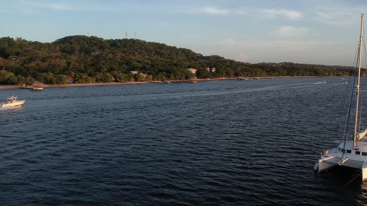 lancha rápida blanca sobre una superficie clara de mar turquesa con botes hacia una isla