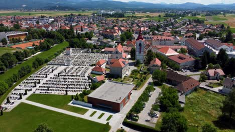 aerial flyover church with cemetery in small slovenian village during sunny day