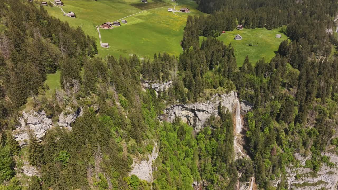 Aerial view of Seerenbach falls in Betlis, Switzerland, forested cliffs, waterfall and peaceful Swiss meadows with mountain cabins