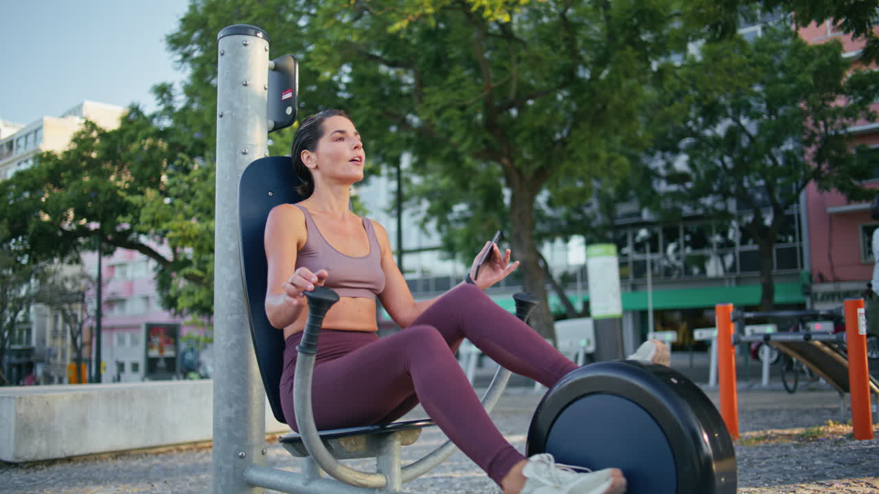 목적이 있는 운동선수가 드폰에서 메시지에 응답하고, 페달을 회전시키고, 자전거 기계를 회전시킨다.