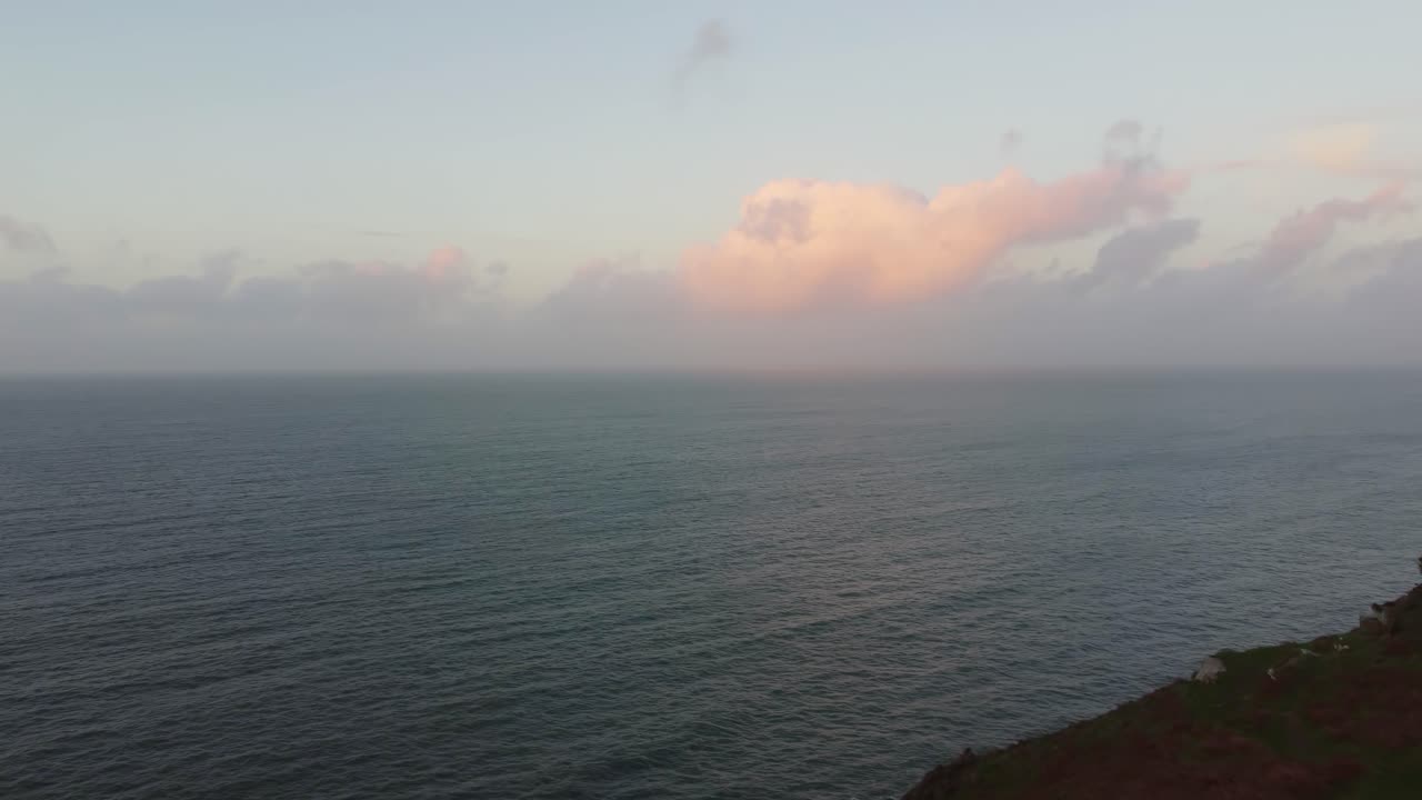 tiro aéreo empujando hacia el mar al atardecer con excursionista admirando la vista al mar en el valle de las rocas uk 4k