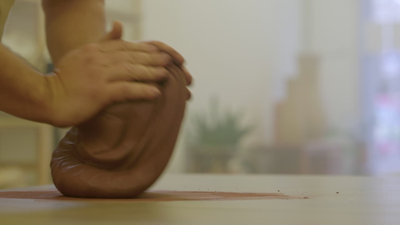 centrándose lentamente en la cerámica las manos del artesano rodando material de arcilla en bruto en la superficie del taller