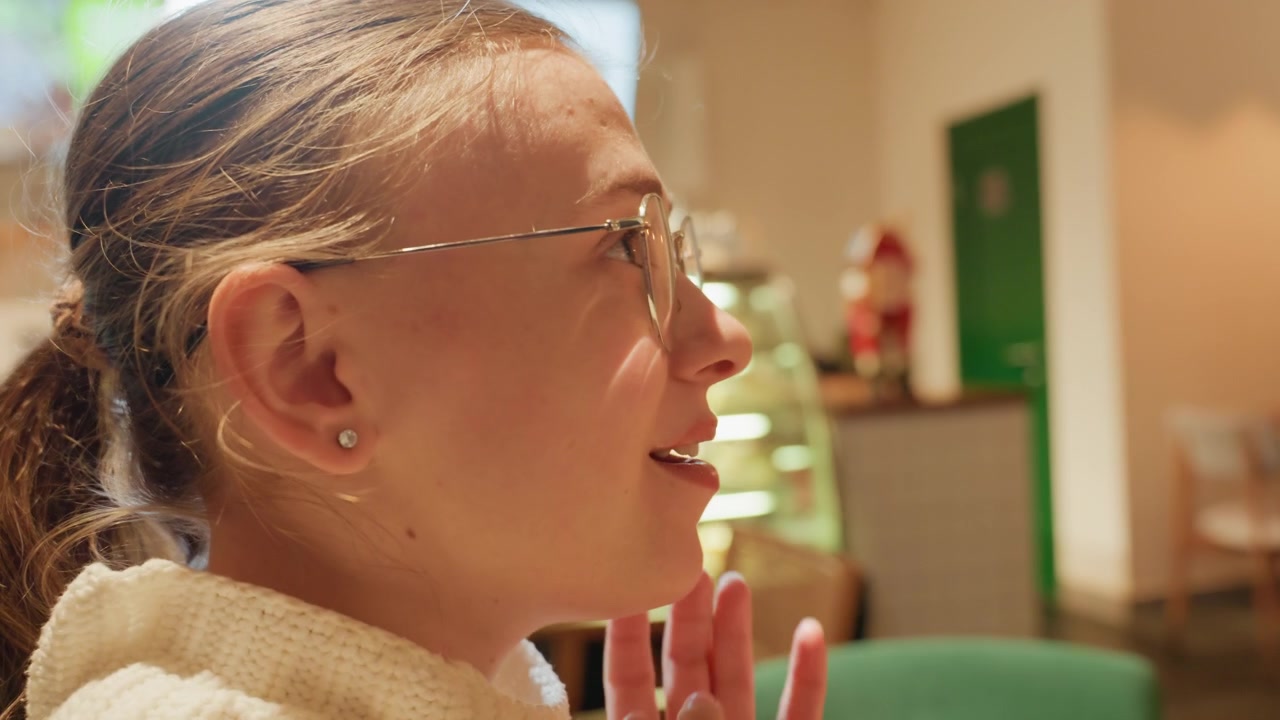 Young Woman Puts On Her Glasses in a Cafe