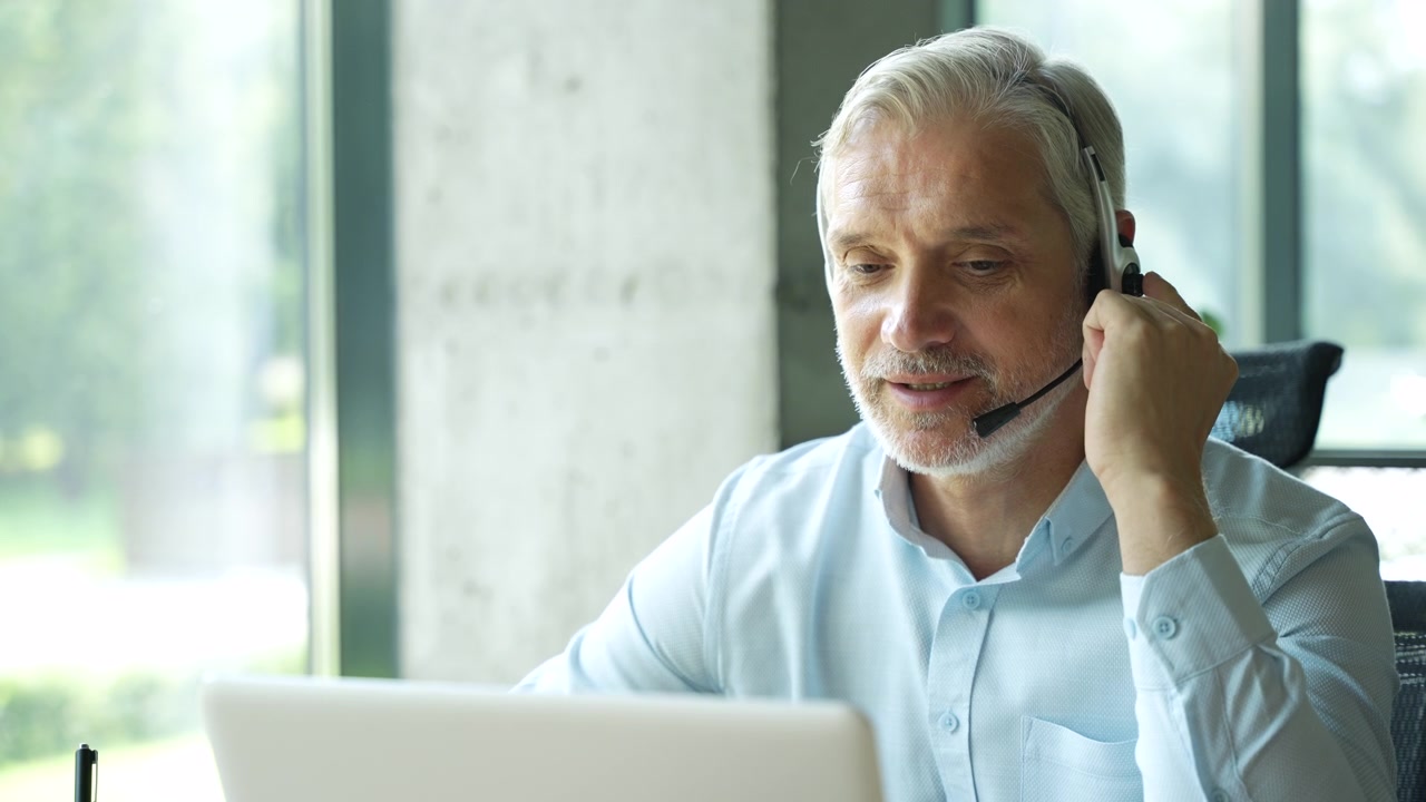 Moden forretningsmand iført headset arbejder på bærbar computer på kontor