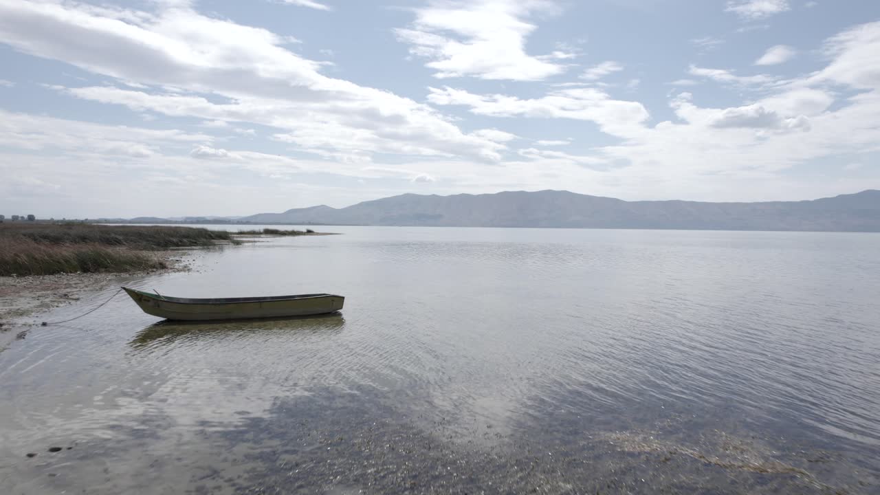 Video con un drone sul Lago di Scutari in Albania, su una vecchia barca di legno in primo piano, sorpassandola su diversi piani a livello dell'acqua