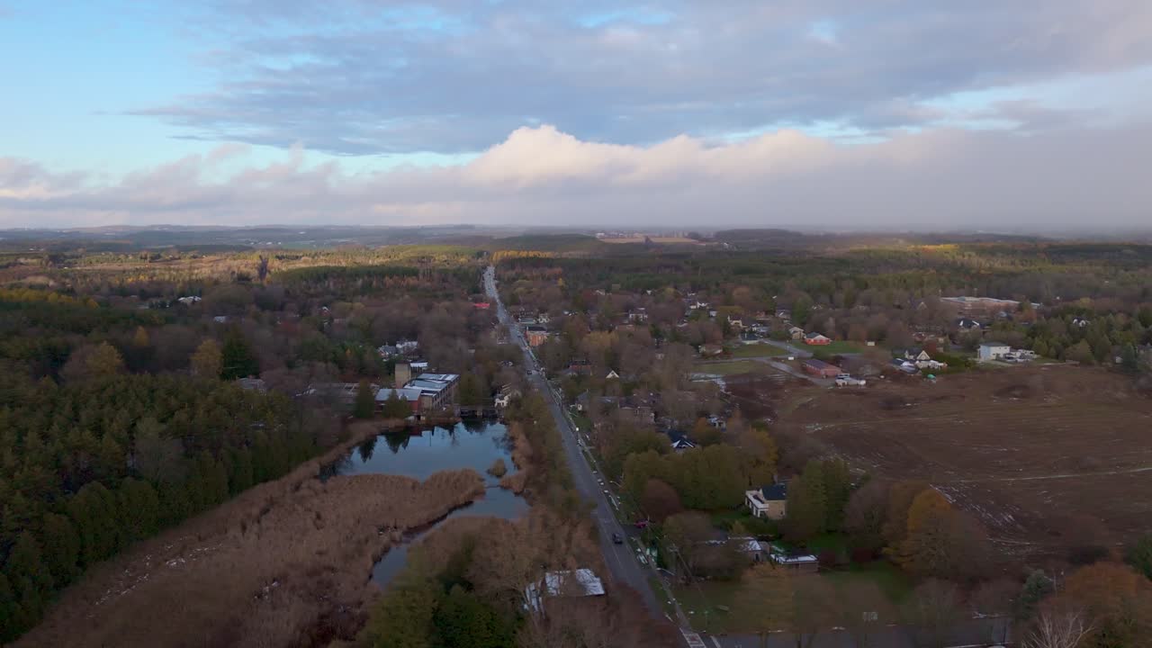Plano aéreo deslizante da cidade de Alton ao pôr do sol, durante o final do outono, em Caledon, Ontário, Canadá.