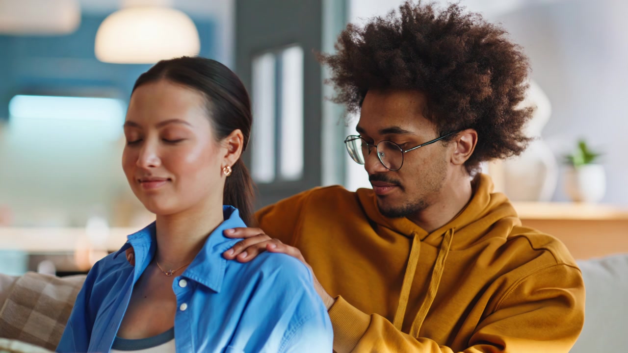 Closeup boyfriend giving girlfriend shoulder massage on sofa at home